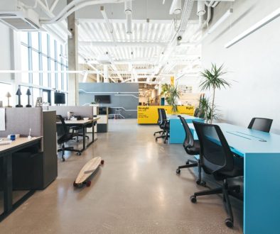 Open-plan office desking area with a blue feature table and exposed ceiling